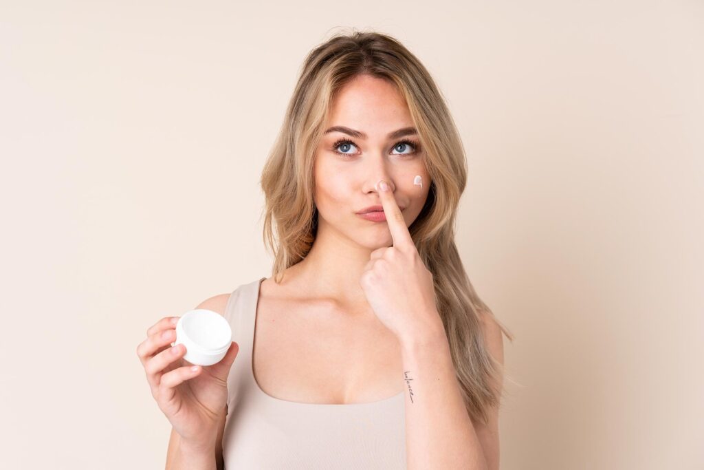 teenager-blonde-girl-with-moisturizer-isolated-wall