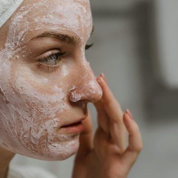 Zena sa belom trakom na glavi nanosi SPF na lice